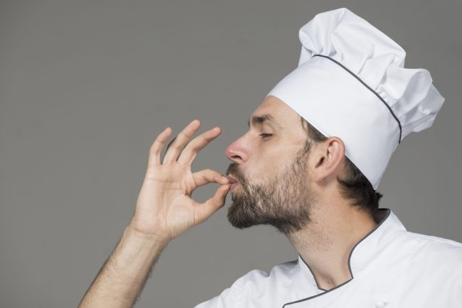 chef-masculin-uniforme-blanc-faisant-savoureux-signe-fond-gris